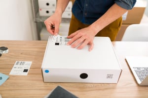 primer-plano-de-manos-masculinas-poniendo-una-etiqueta-de-envio-en-un-paquete-y-organizando-los-pedidos-de-los-clientes-en-linea